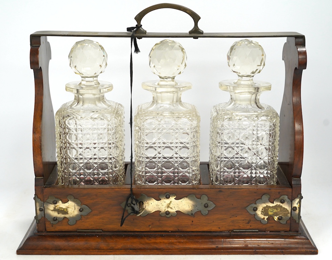 A three bottle tantalus with key, 38cm wide. Condition - fair, chipping to the stoppers